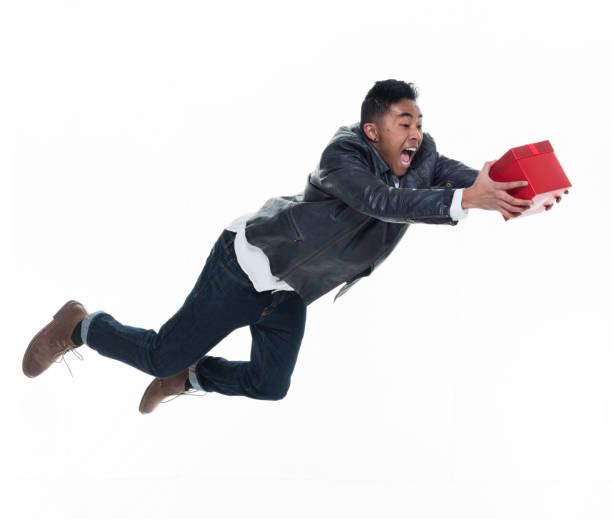 istock Daring young handsome male in mid air falling and holding a gift box 925239208