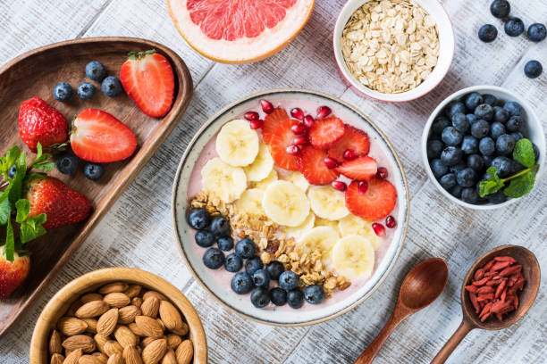 bol smoothie banane, fraise, myrtille, granola et grenade - cereal breakfast granola healthy eating photos et images de collection