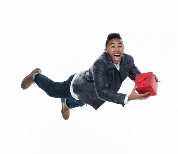 istock Daring young handsome male in mid air falling and holding a gift box 925240312