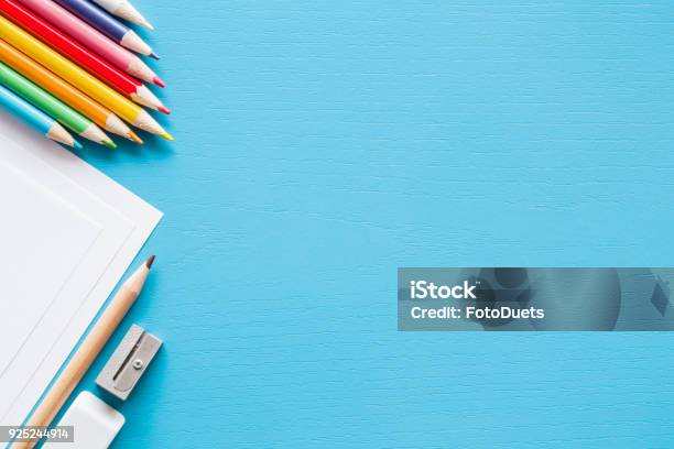 Colorful Pencils White Papers And Metal Pencil Sharpener Empty Place For Text Or Drawing On The Blue Background Childhood Creative Art Concept Flat Lay Stock Photo - Download Image Now