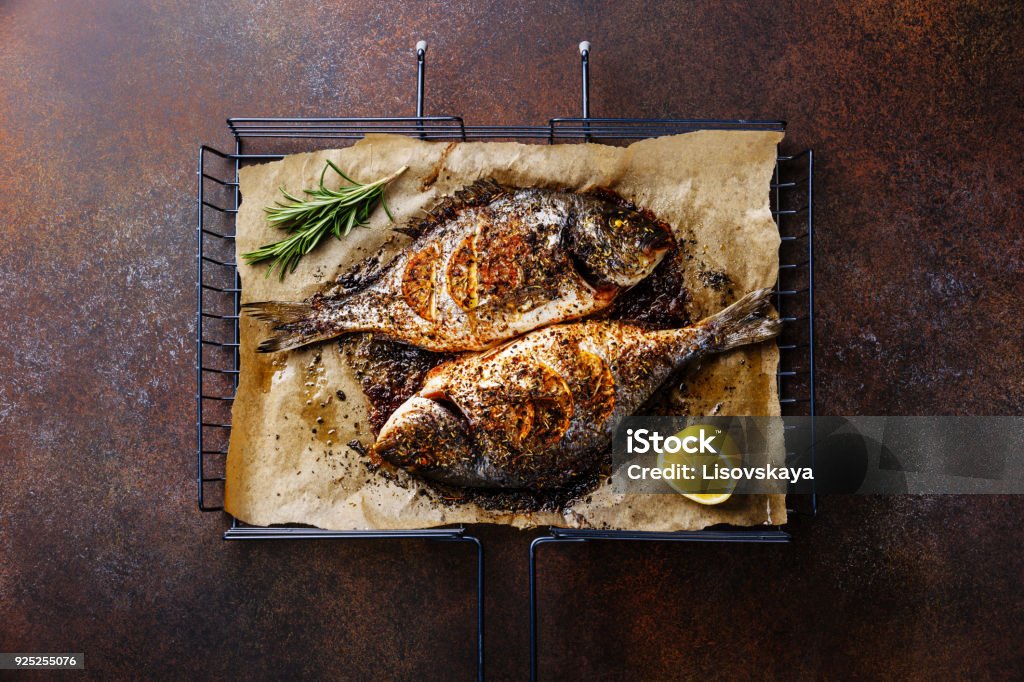 Dorado de poissons grillés sur du métal grill grille au citron et romarin - Photo de Poisson libre de droits