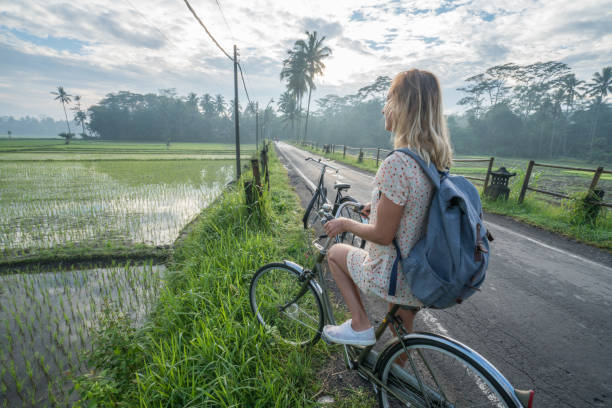 istock Young woman on bicycle stops to admire rice fields, Indonesia 925255232