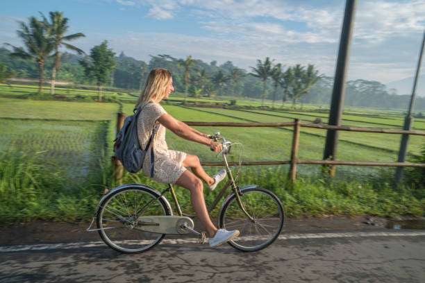 istock Young woman riding bicycle near rice fields, Indonesia 925255848
