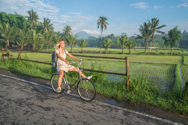 istock Young woman riding bicycle near rice fields, Indonesia 925255994