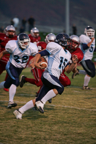 A running back sprints on an sweep play in American football.
