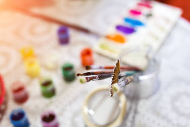 Close up detail of paints and paintbrushes on the table. Hobbies, art, creativity and leisure concepts. Selective focus