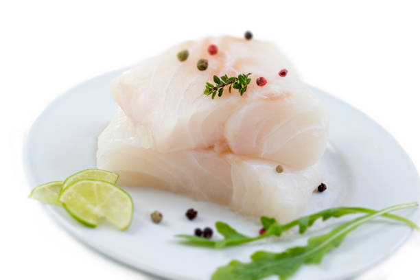 istock close up Fresh raw cod fish fillet on a plate with parsley and lemon isolated white background 925260624