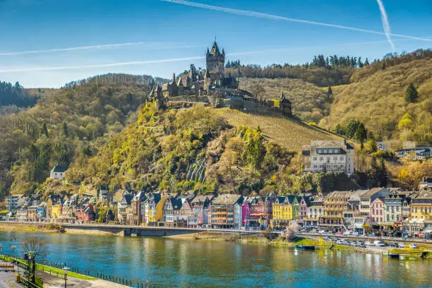 Beautiful view of the historic town of Cochem with famous Reichsburg castle on top of a hill and scenic Moselle river on a sunny day with blue sky and clouds in springtime, Rheinland-Pfalz, Germany