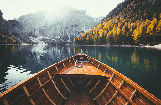 Scenic view of traditional wooden rowing boat gliding on famous Lago di Braies in the Italian Dolomites on a beautiful sunny day in fall with retro vintage filter effect, South Tyrol, Italy