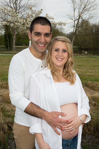 Pregnant woman with husband walking on meadow