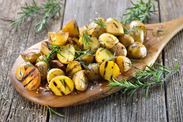 Vegan cuisine: Grilled baby potatoes with rosemary served on a wooden board