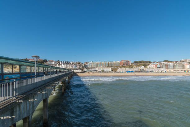 A view along Boscombe Pier in Bournemouth inland A view along Boscombe Pier in Bournemouth. People walking and sitting on the popular landmark. The pier includes a mini-golf course, various challenge holes can be seen. boscombe photos stock pictures, royalty-free photos & images