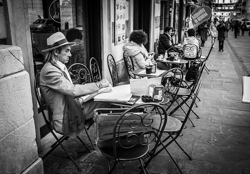 Genoa, Italy - April 21, 2016: Italian men dressed like gentleman reeds the morning newspapers at the outdoor table small cozy cafe  in Genoa, Italy
