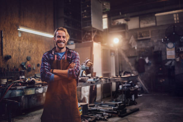 Happy professional craftsman standing in workshop with tools Portrait of smiling mechanic standing in garage workshop with professional equipment woodshop stock pictures, royalty-free photos & images