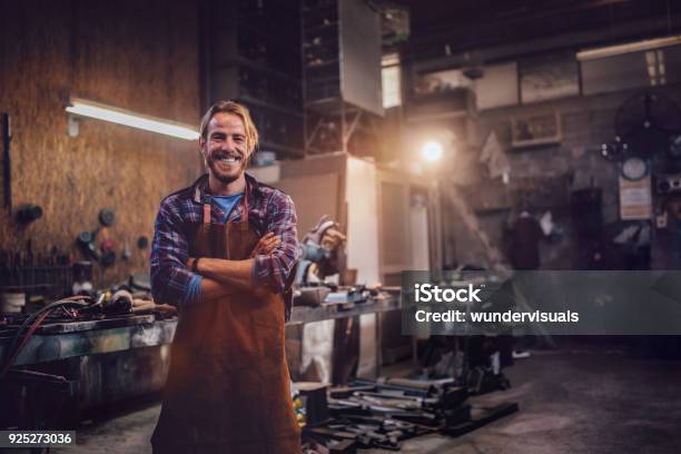 Happy Professional Craftsman Standing In Workshop With Tools - Fotografias de stock e mais imagens de Pequenas Empresas