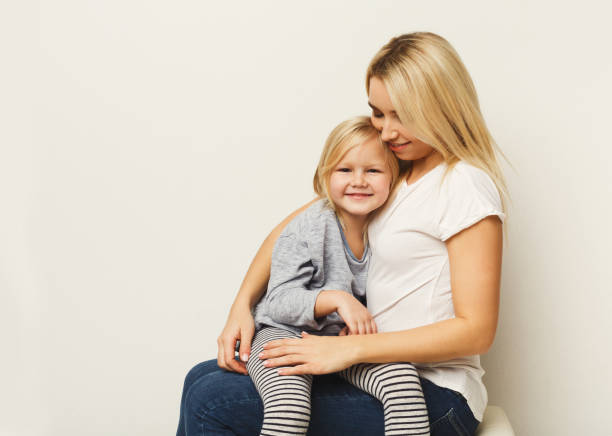 istock Happy mother and daughter embracing at white studio background 925279770
