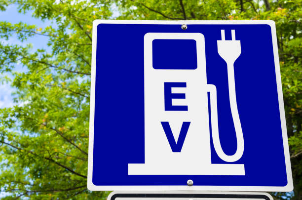 Close up of a Sign indicating an Electric Vehicle Recharging Point Close photo of a Blue Sign indicating an Electric Vehicle Recharging Point. Green Trees are Visible in Background. Ecological Mode of Transport. vancouver island photos stock pictures, royalty-free photos & images