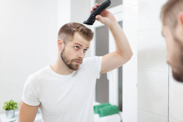 istock Handsome man cutting his own hair with a clipper 925279966
