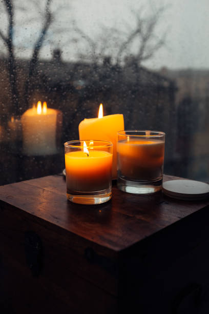 istock Three burning candles on table, cozy rainy day an home 925280914