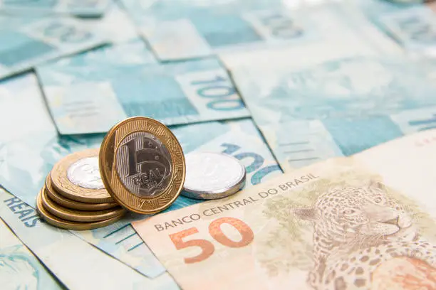 Money from Brazil. Notes of Real, Brazilian currency. Concept of savings, salary, payment and funds. Full frame with money banknotes and One Real Coin the foreground.