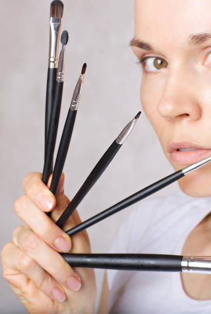 istock Young lady is keeping make up brushes kit close to her face. 925282102