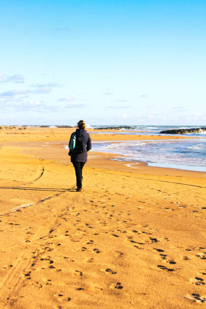 istock Sicily, Italy: Lone Woman Walking on Winter Beach 925283302