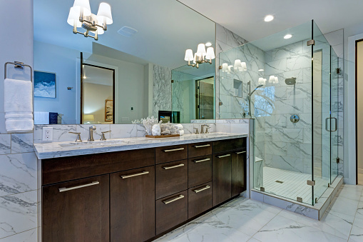 Incredible master bathroom with Carrara marble tile surround, modern glass walk in shower, espresso dual vanity cabinet and a freestanding bathtub.