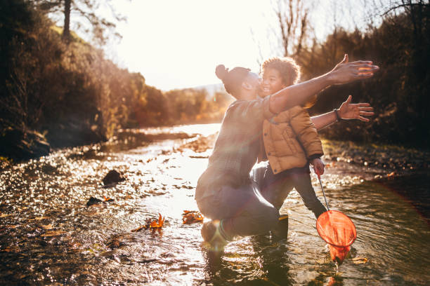 istock Successful father and son embracing after catching fish in river 925288396