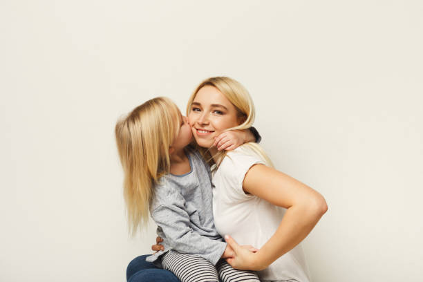 istock Happy mother and daughter embracing at white studio background 925289604