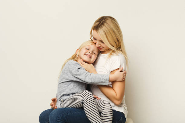 istock Happy mother and daughter embracing at white studio background 925289714