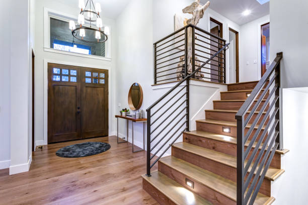 Chic entrance foyer with high ceiling and white walls. Chic entrance foyer with high ceiling and wide staircase with lights and contemporary railing. New Custom built home interior. customised stock pictures, royalty-free photos & images