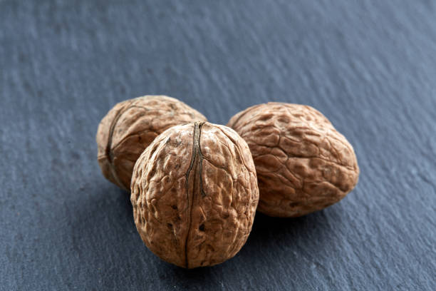 istock A stack of walnuts piled together and isolated on dark background, shallow depth of field, selective focus 925302736