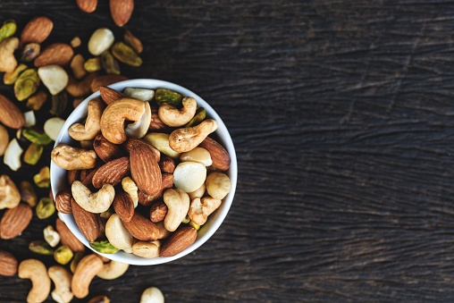 Healthy food and snack : mixed nuts in white ceramic bowl from above,  Walnut, pistachios, almonds, hazelnuts and cashews.