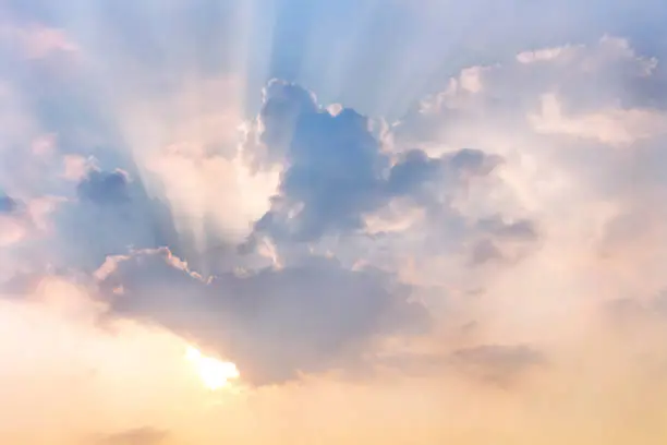 Clouds and sun shines through rays of light in the illuminated picturesque sky.