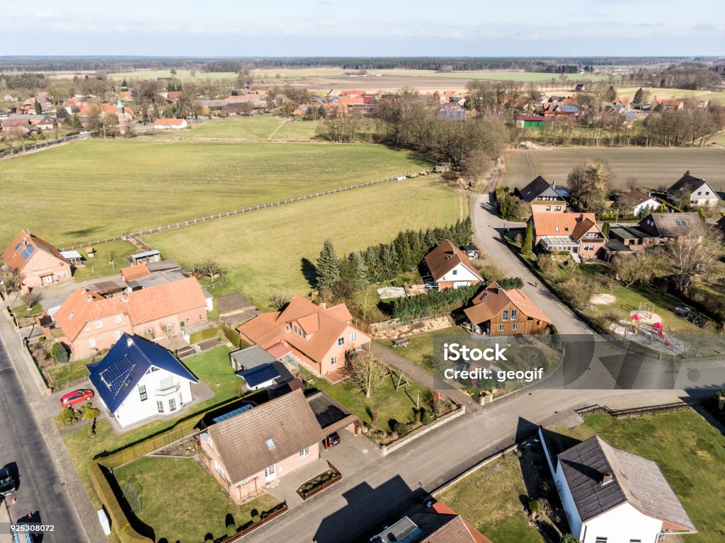 Obliquely photographed aerial view of the edge of a village with houses and a grassy area in the background, which forms a gap in the current location. Obliquely photographed aerial view of the edge of a village with houses and a grassy area in the background, which forms a gap in the current location., made with drone Above Stock Photo