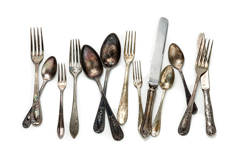 Group of vintage silverware shot from above on white background. The pieces are stained and weathered and arranged side by side in a messy way. High key DSRL studio photo taken with Canon EOS 5D Mk II and Canon EF 70-200mm f/2.8L IS II USM Telephoto Zoom Lens