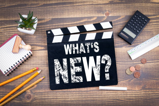 what's new? movie clapper on a wooden desk - building feature imagens e fotografias de stock