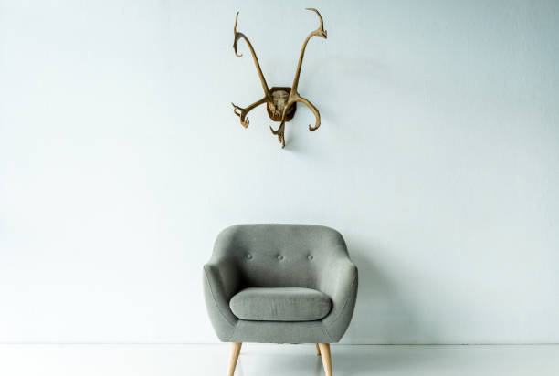 Gray armchair with wooden legs and antlers on a wall