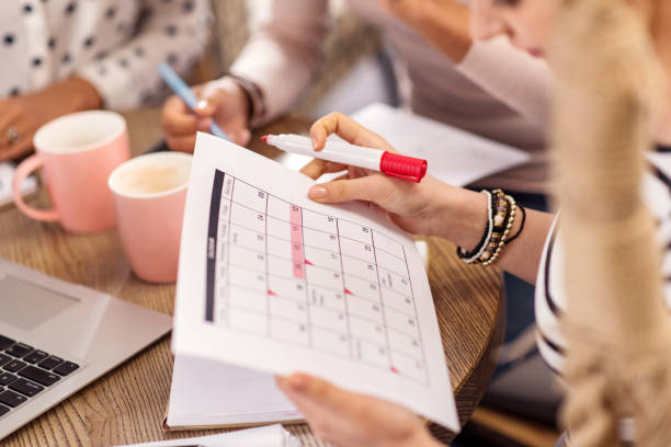 Tender female hands holding calendar According to plan. Young smooth female hands carrying calendar while planning agenda and marking with liner busy restaurant tables stock pictures, royalty-free photos & images