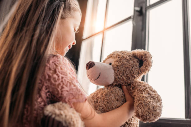 istock adorable little child playing with teddy bear on windowsill 925318966
