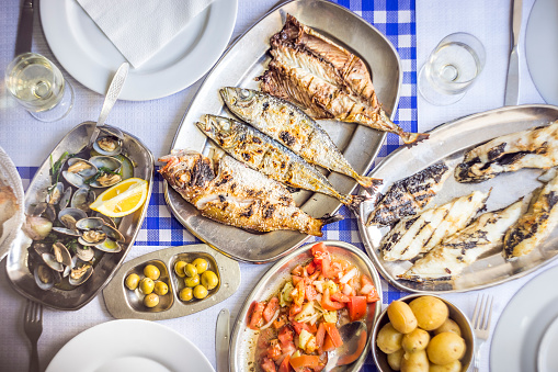 Fish feast: sea bass, golden, horse mackerel accompanied with tomato salad, clams, bread and white wine, Portugal