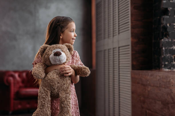 istock beautiful little child holding teddy bear at home 925323686