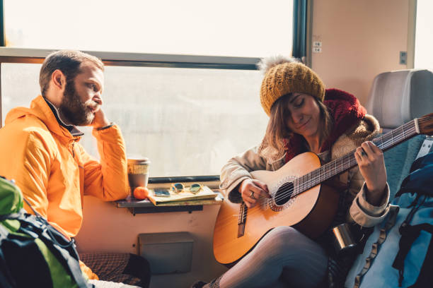 istock Couple traveling in train and playing the guitar 925323868
