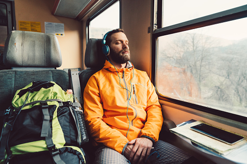 Young man with headphones napping in the train