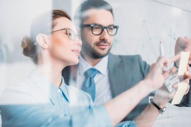 istock successful businesspeople drawing graphs on glass presentation board 925327804