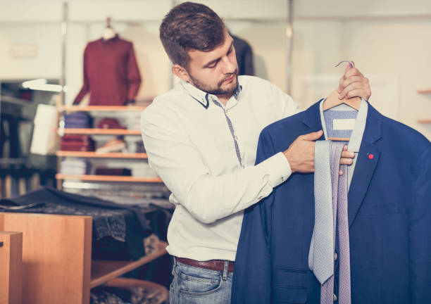 istock Handsome adult guy  choosing modern jacket in men store 925328094
