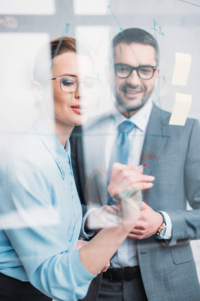 istock happy businesspeople drawing graphs on glass presentation board 925331970