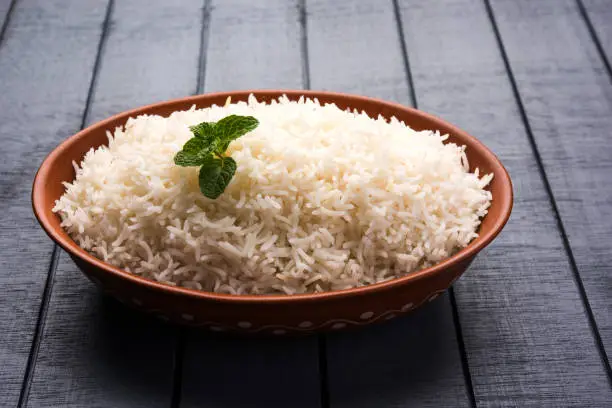 Photo of Cooked plain white basmati rice in terracotta bowl over plain or wooden background