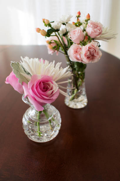 istock Two crystal vases with roses on table in front of window 925353148
