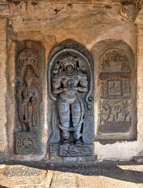 Indian sculptures depicting a woman, displaying stylized feminine features, a demigod and a historical battle, inside Chennakeshava Complex temple, Bellur, India